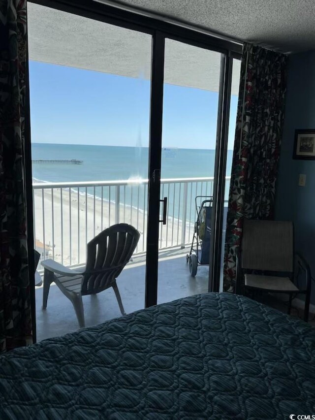 9550 Shore Dr Unit 1721, Myrtle Beach, SC 29572 - bedroom with view of water and beach, a textured ceiling, and a wall of windows