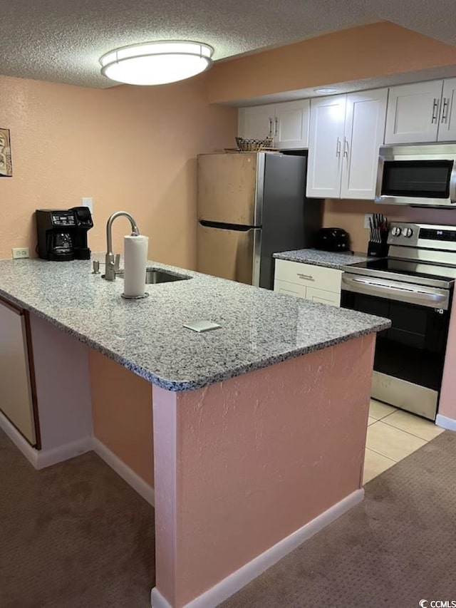 9550 Shore Dr Unit 1721, Myrtle Beach, SC 29572 - kitchen featuring stainless steel appliances, a textured ceiling, a sink, white cabinets, and a peninsula