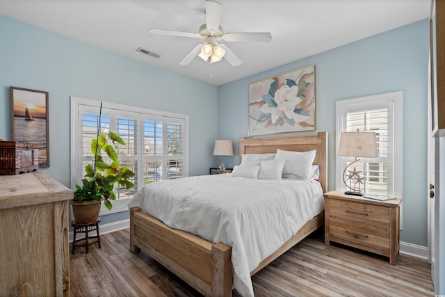 bedroom featuring multiple windows, hardwood / wood-style flooring, and ceiling fan