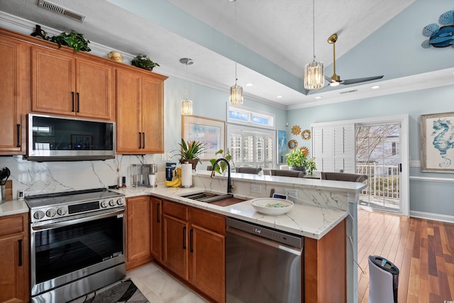 kitchen featuring stainless steel appliances, sink, pendant lighting, and kitchen peninsula