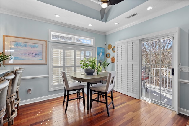 dining space featuring a raised ceiling, ornamental molding, and hardwood / wood-style floors