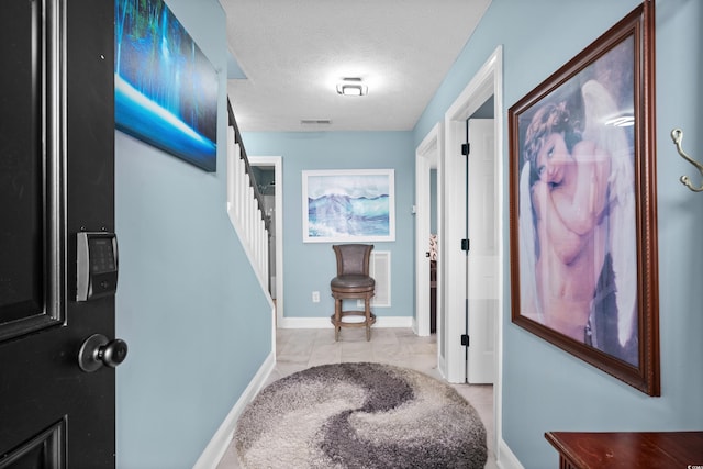 hall with a textured ceiling and light tile patterned floors