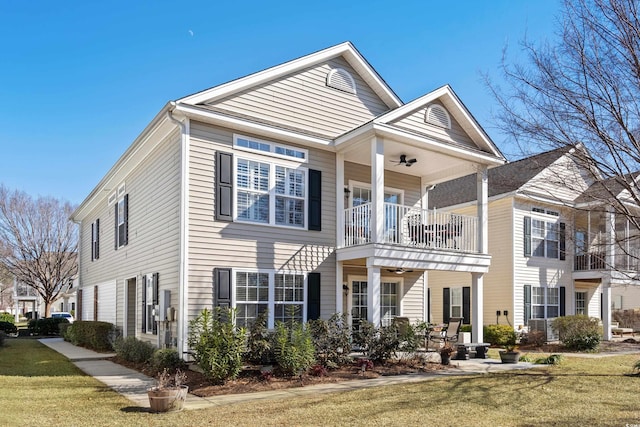 view of front of house featuring ceiling fan, a balcony, and a front lawn