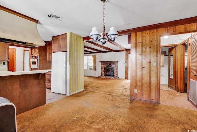 kitchen featuring a fireplace, wood walls, decorative light fixtures, a chandelier, and white appliances