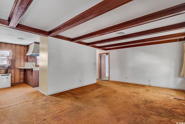 unfurnished living room with beamed ceiling, light carpet, and wood walls