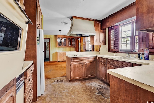 kitchen with sink, white appliances, hanging light fixtures, kitchen peninsula, and wall chimney exhaust hood