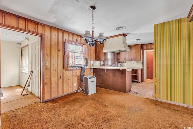 kitchen featuring a breakfast bar, island range hood, kitchen peninsula, pendant lighting, and light colored carpet