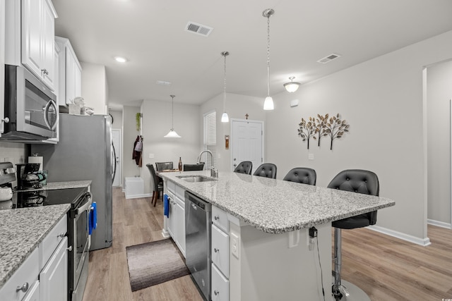 kitchen featuring a breakfast bar, sink, an island with sink, stainless steel appliances, and white cabinets