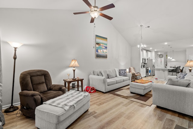 living room with high vaulted ceiling, ceiling fan with notable chandelier, and light hardwood / wood-style floors