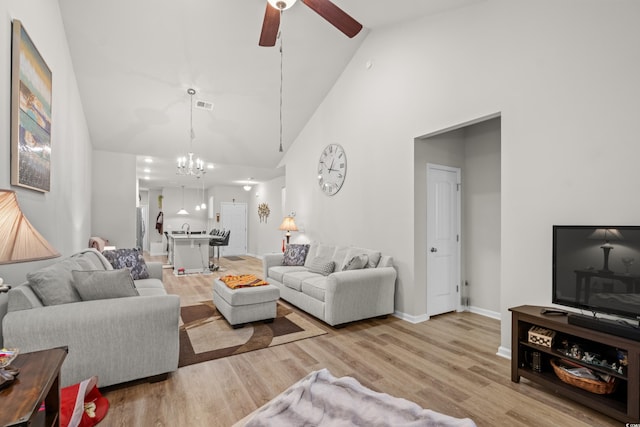 living room with high vaulted ceiling, ceiling fan with notable chandelier, and light wood-type flooring