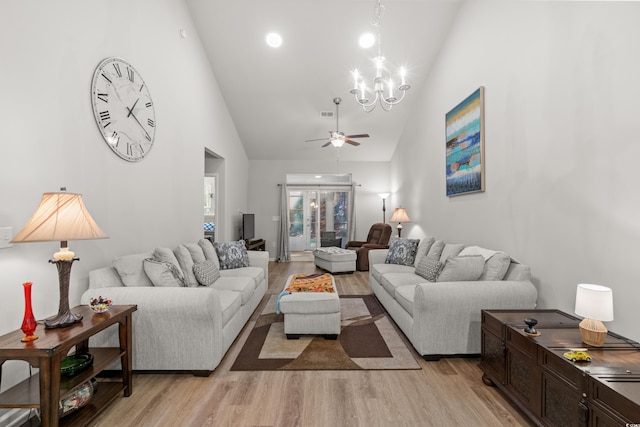 living room with ceiling fan with notable chandelier, high vaulted ceiling, and light wood-type flooring