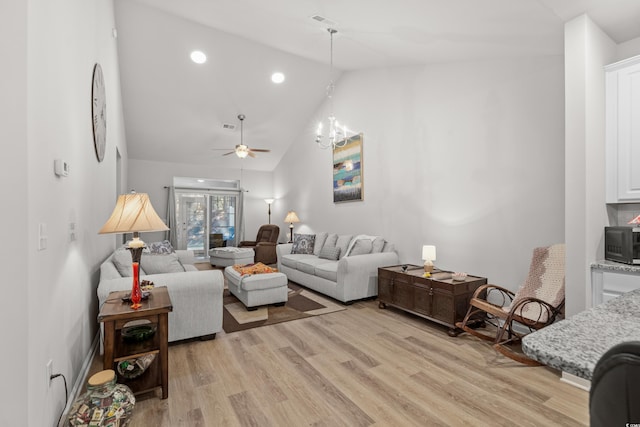 living room with ceiling fan with notable chandelier, light hardwood / wood-style flooring, and high vaulted ceiling