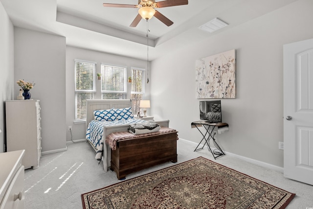 carpeted bedroom featuring ceiling fan and a tray ceiling