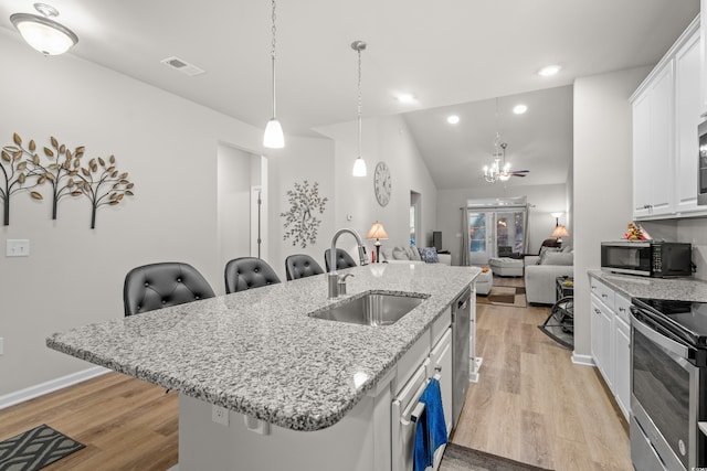 kitchen featuring sink, a breakfast bar area, appliances with stainless steel finishes, white cabinetry, and a kitchen island with sink