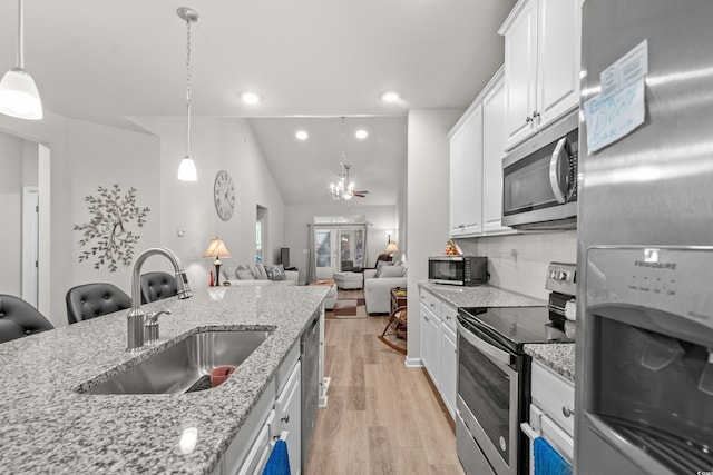 kitchen featuring pendant lighting, sink, appliances with stainless steel finishes, white cabinetry, and light stone countertops