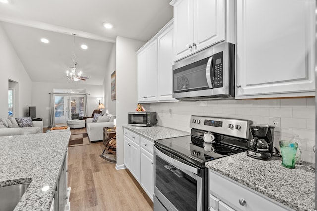 kitchen with appliances with stainless steel finishes, white cabinetry, light stone countertops, light hardwood / wood-style floors, and decorative backsplash