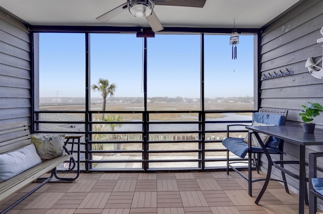 sunroom / solarium featuring a wealth of natural light, ceiling fan, and a water view