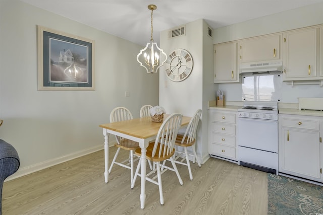 kitchen with pendant lighting, white electric range oven, a chandelier, and light hardwood / wood-style flooring