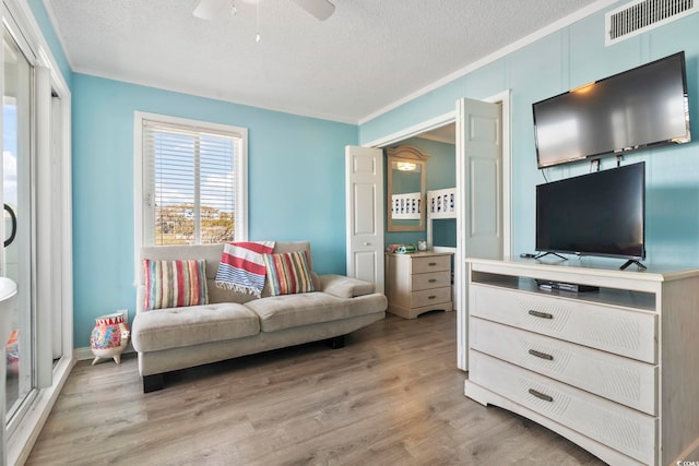 living room with ornamental molding, light hardwood / wood-style flooring, and a textured ceiling