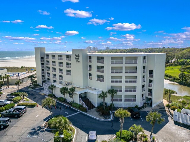 view of building exterior with a beach view and a water view