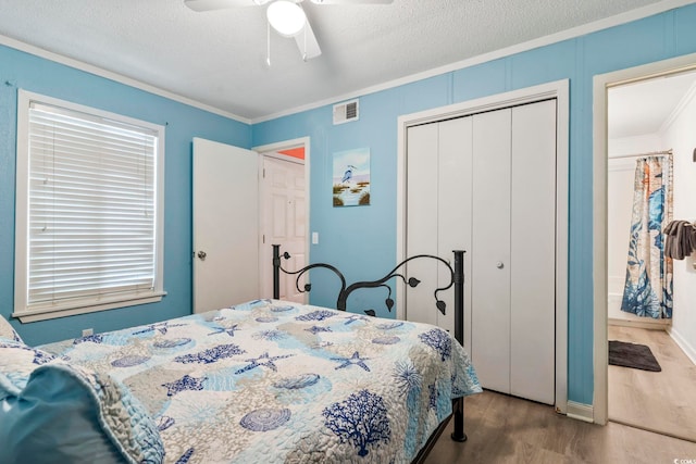 bedroom featuring ceiling fan, hardwood / wood-style floors, ornamental molding, a textured ceiling, and a closet