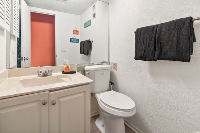 bathroom featuring vanity, a textured ceiling, and toilet