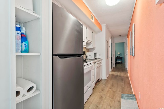 kitchen with white appliances, light hardwood / wood-style floors, a textured ceiling, and white cabinets