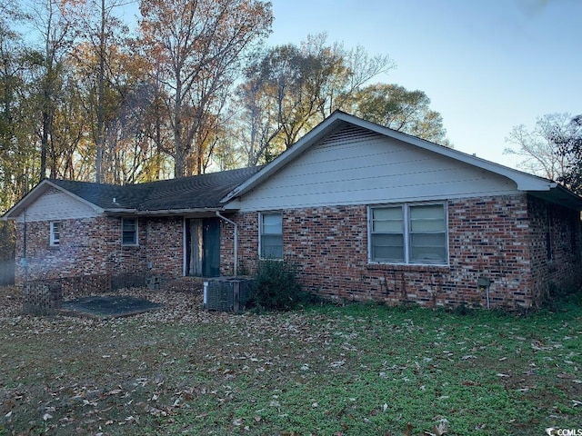 exterior space with brick siding, central AC unit, and a yard