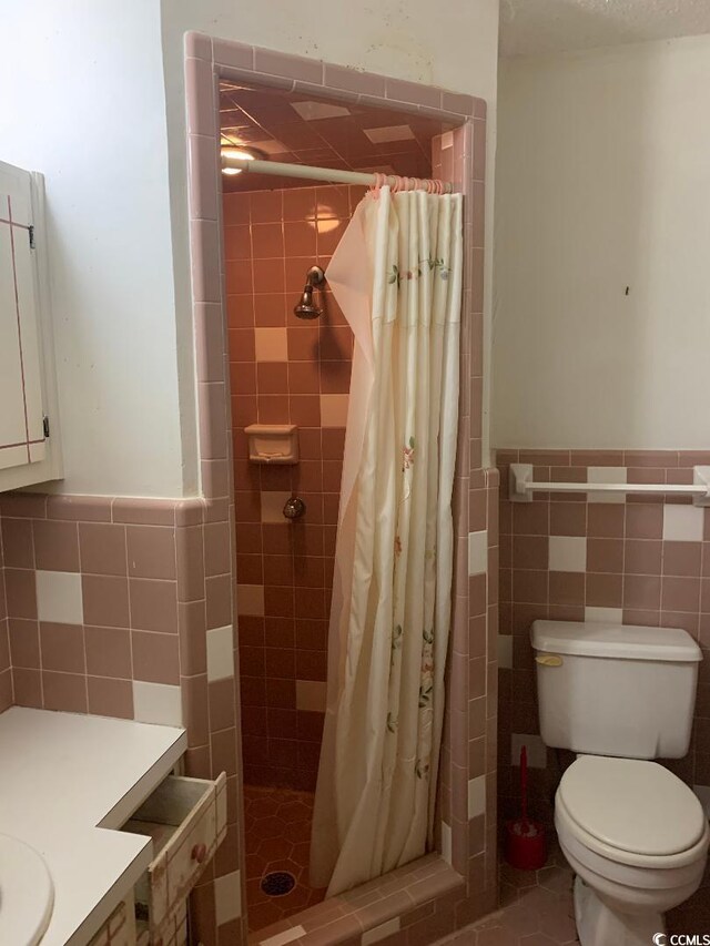 bathroom with tile walls, toilet, and walk in shower