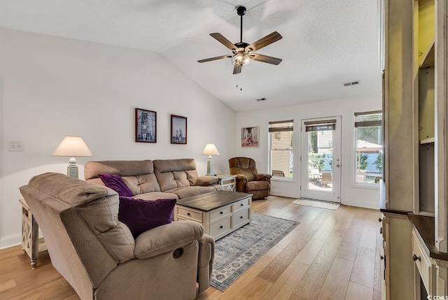 living room featuring vaulted ceiling, ceiling fan, light hardwood / wood-style floors, and a textured ceiling