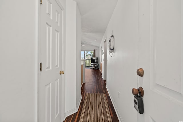 corridor with dark wood-type flooring and vaulted ceiling