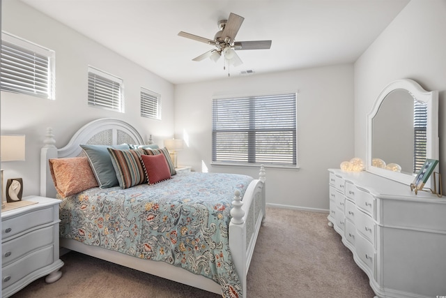 bedroom with light carpet, ceiling fan, visible vents, and baseboards