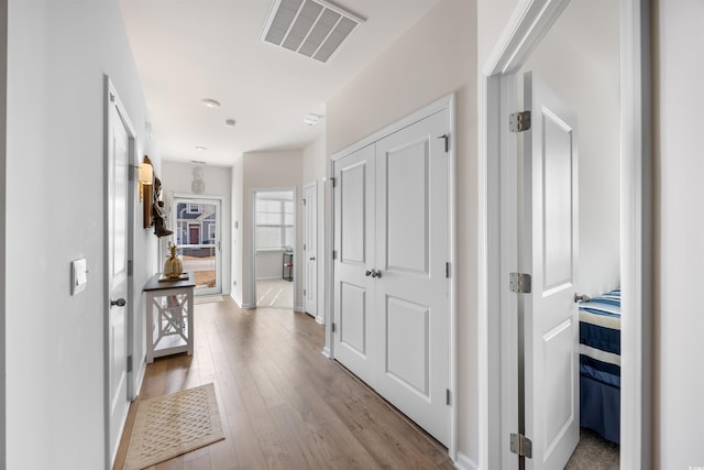 hall featuring light wood finished floors and visible vents