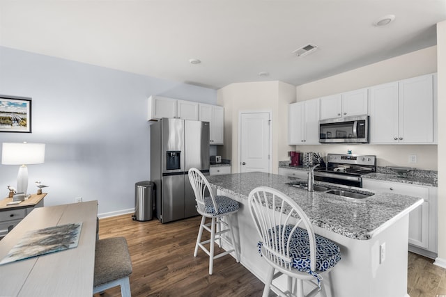 kitchen with white cabinets, stone counters, a center island with sink, and stainless steel appliances