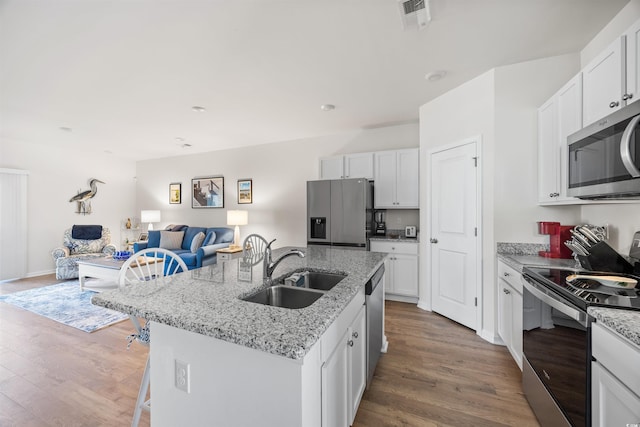 kitchen featuring white cabinetry, stainless steel appliances, a sink, and open floor plan