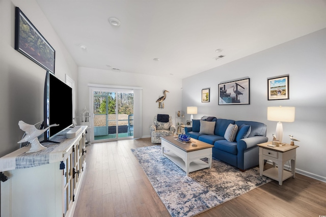 living area featuring visible vents, baseboards, and wood finished floors