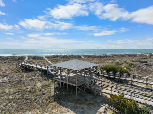 dock area featuring a water view, an exterior structure, and a view of the beach