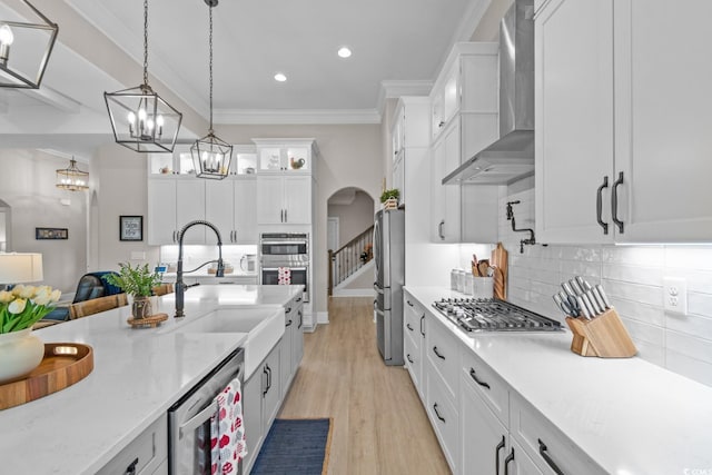 kitchen with sink, appliances with stainless steel finishes, wall chimney range hood, beverage cooler, and white cabinets