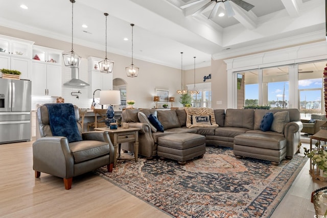 living room featuring ceiling fan, beam ceiling, a high ceiling, ornamental molding, and light wood-type flooring