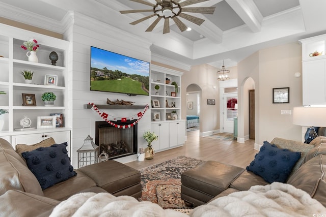 living room featuring ornamental molding, built in features, and light hardwood / wood-style flooring