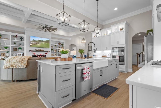 kitchen with pendant lighting, sink, appliances with stainless steel finishes, a kitchen island with sink, and light hardwood / wood-style floors