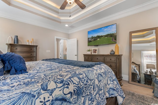 bedroom with a raised ceiling, ornamental molding, ceiling fan, and light hardwood / wood-style floors