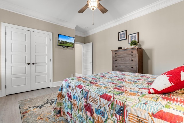 bedroom with ceiling fan, ornamental molding, a closet, and light wood-type flooring