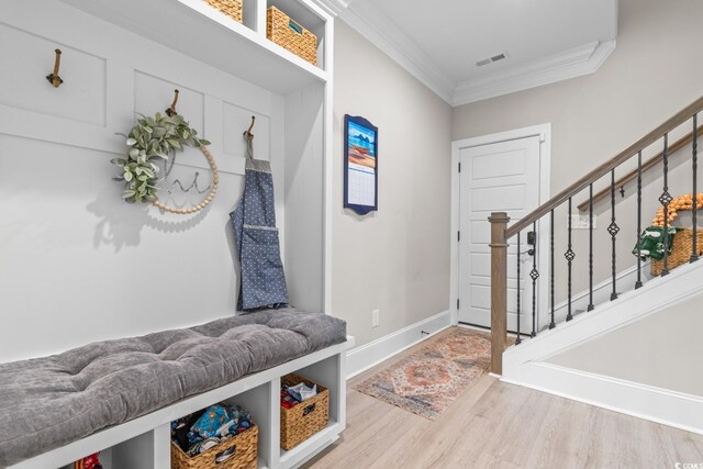 clothes washing area with sink, cabinets, light wood-type flooring, ornamental molding, and washing machine and dryer