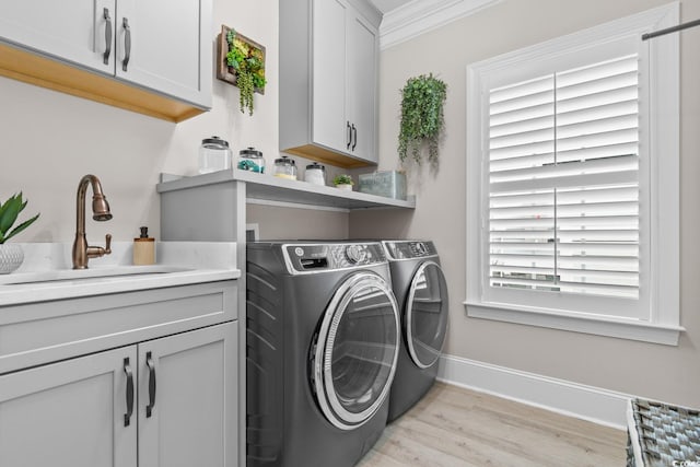 laundry area featuring sink, cabinets, separate washer and dryer, light hardwood / wood-style flooring, and ornamental molding