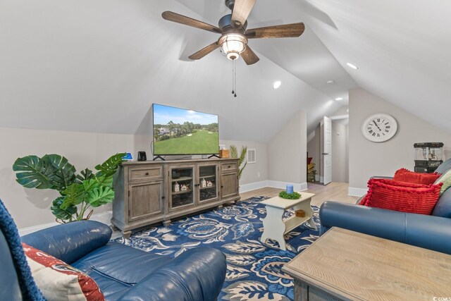 living room with hardwood / wood-style flooring, ceiling fan, and vaulted ceiling