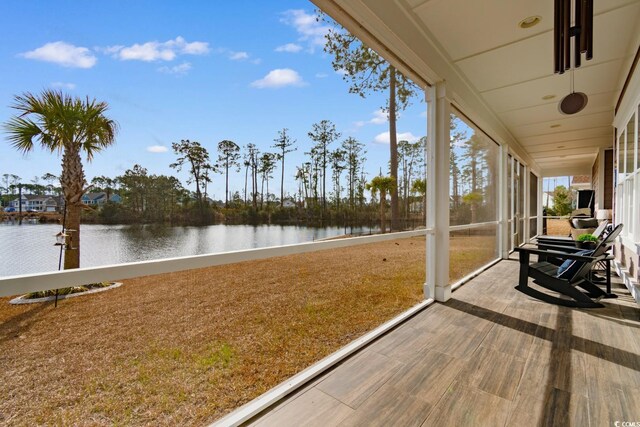 sunroom featuring a water view and ceiling fan