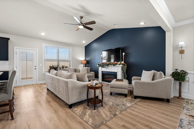 living room featuring vaulted ceiling, ornamental molding, ceiling fan, and light wood-type flooring