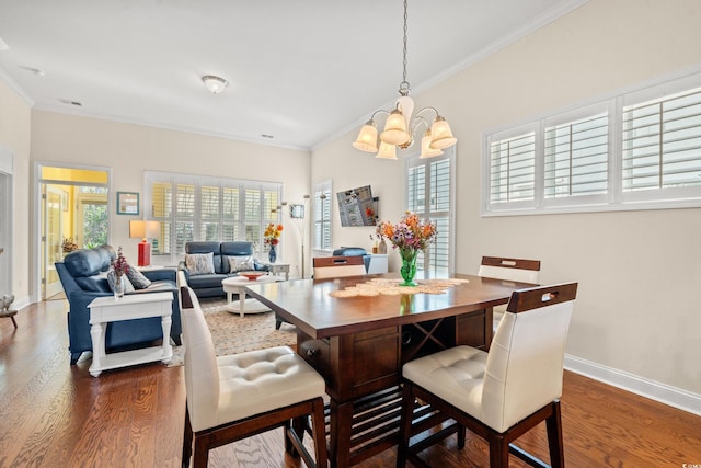 dining area featuring dark wood-type flooring, ornamental molding, and an inviting chandelier