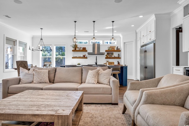 living room with crown molding, a notable chandelier, and light hardwood / wood-style flooring